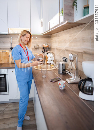 Smiling nurse preparing coffee in the kitchen during a break Smiling nurse preparing coffee in the kitchen during a break 133857914