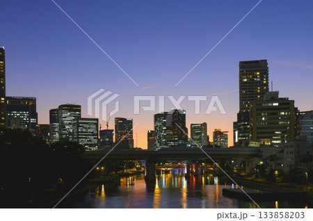 夕暮れの空と都市のビル群、水面越しの景観 133858203