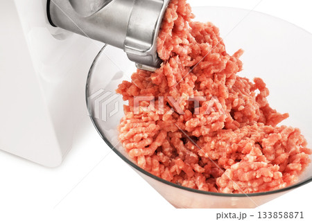 A close-up of fresh, ground meat being extruded from a metal meat grinder and collecting in a clear glass bowl. High quality photo A close-up of fresh, ground meat being extruded from a metal meat grinder and collecting in a clear glass bowl. High quality photo 133858871