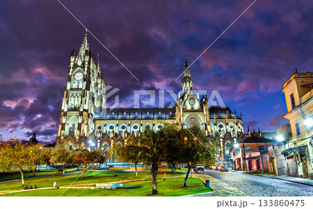Illuminated Basilica del Voto Nacional stands against cloudy twilight sky in Quito, Ecuador. Neo-Gothic church features twin towers and large rose window in historic center Illuminated Basilica del Voto Nacional stands against cloudy twilight sky in Quito, Ecuador. Neo-Gothic church features twin towers and large rose window in historic center 133860475