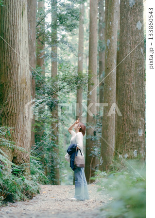 聖地巡礼で杉林を歩く女性 133860543