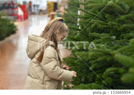 Small girl chooses a Christmas tree in the market. Small girl chooses a Christmas tree in the market. 133860954
