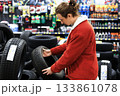Man choosing a car tire in an auto parts store surrounded by wheels and vehicle accessories. High quality photo 133861078
