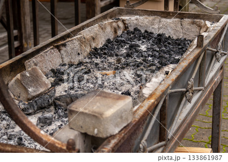 The aftermath of a food festival shows a grill filled with ash and charcoal, highlighting a busy outdoor market scene The aftermath of a food festival shows a grill filled with ash and charcoal, highlighting a busy outdoor market scene 133861987