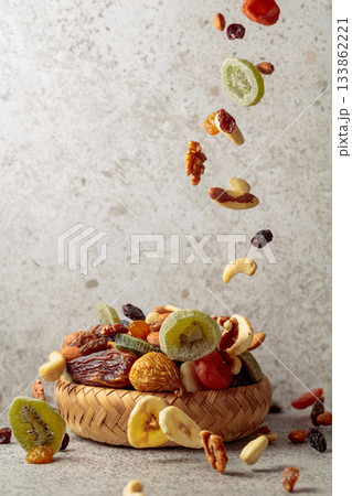 Mix of dried fruits and nuts in motion on a gray background. Mix of dried fruits and nuts in motion on a gray background. 133862221