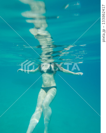 A young woman in a black bikini in turquoise water. Only the body is viable in the photo A young woman in a black bikini in turquoise water. Only the body is viable in the photo 133862417
