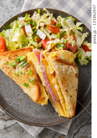 One-Pan Egg Toast with ham and gooey melted cheese served with fresh salad closeup on the plate on the table. Vertical top view 133862647