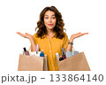 A woman shows shopping bags full of beauty products, presenting her purchases. 133864140