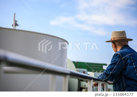 フェリーの甲板で海を眺める60代の日本人男性の後ろ姿 フェリーの甲板で海を眺める60代の日本人男性の後ろ姿 133864177