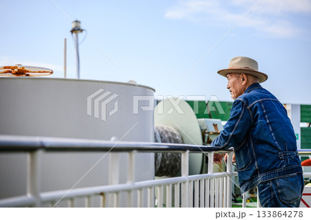 デッキで海を眺めるデニムジャケット姿の日本人シニア男性 133864278