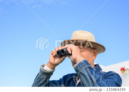 双眼鏡で遠くを眺めるシニア男性、フェリーで 133864295