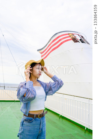 麦わら帽子をかぶった若い日本女性がフェリーの甲板で夏の日差しを楽しむ旅行の瞬間 麦わら帽子をかぶった若い日本女性がフェリーの甲板で夏の日差しを楽しむ旅行の瞬間 133864359