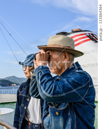 双眼鏡で景色を覗くデニムファッションのシニ 133864364