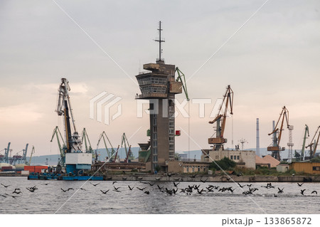 A scenic coastal view of an industrial Varna port featuring cranes and a watchtower A scenic coastal view of an industrial Varna port featuring cranes and a watchtower 133865872