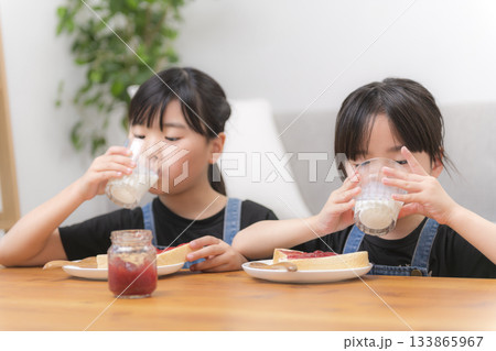 食パンの並んだ食卓で牛乳を飲む女の子 133865967