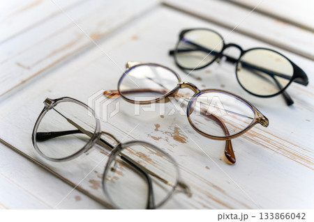 木製テーブルの上に置かれた様々な形状の眼鏡 133866042