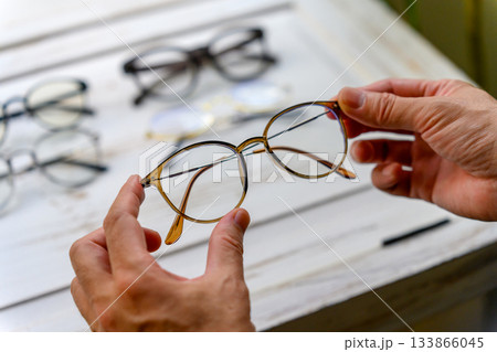 選ばれている丸型メガネを手に取る男性の手元 133866045