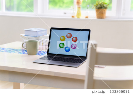 明るい窓辺のデスクに置かれたカラフルな円グラフを表示するノートパソコン 133866051
