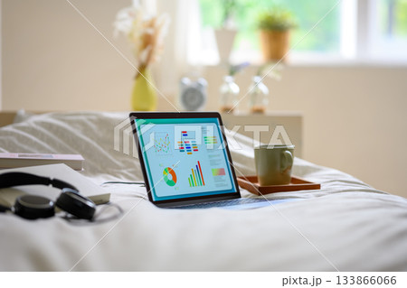 ベッドの上でデータ分析をするノートパソコンと飲み物 133866066