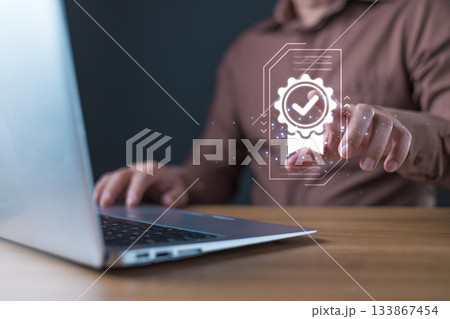 A businessman interacts with a glowing digital icon of a certificate featuring a checkmark, symbolizing quality assurance and trust in digital standards, service, or performance. 133867454