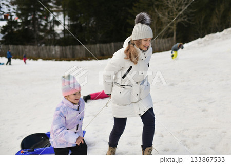 A mother and daughter climbing a mountain with a sled 133867533