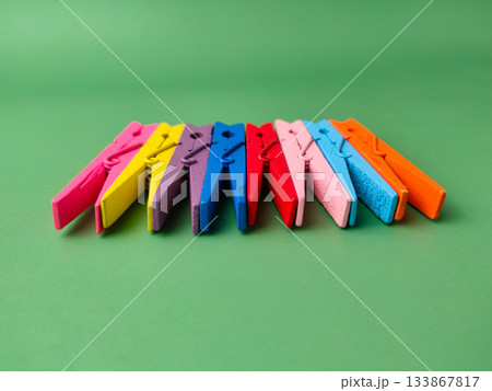 The image shows a row of colorful wooden clothespins on a green background. 133867817