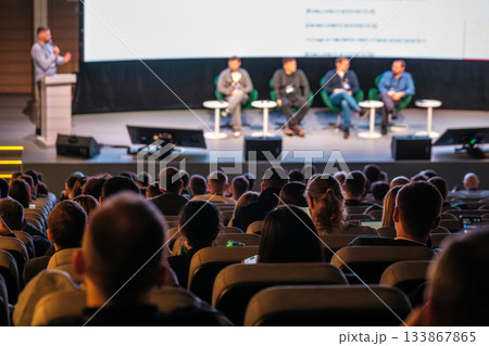Panel discussion on stage with speakers and audience at a conference event 133867865