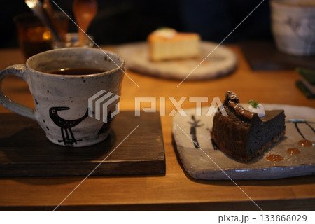 味わい深い黒ゴマケーキとカフェの手描きマグカップで楽しむティータイム 133868029