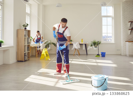 Workers from cleaning service mopping floor and dusting furniture in modern house 133868625