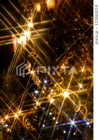 Christmas tree with yellow ribbon, toys. Christmas tree decorated with garlands lots of sparkles.  133869818