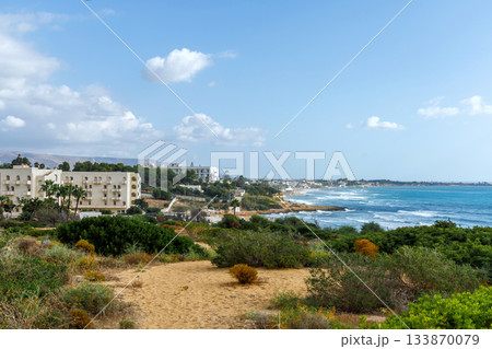 Sicily Italy seascape overlooking a turquoise bay and distant resort skyline 133870079