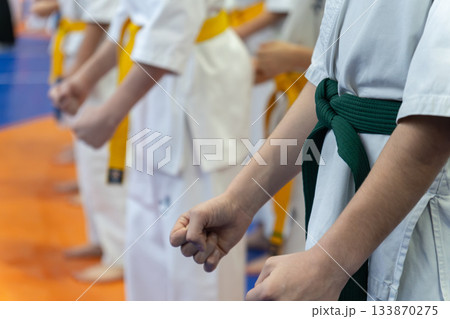 A line of children in white karate uniforms with yellow and green belts A line of children in white karate uniforms with yellow and green belts 133870275