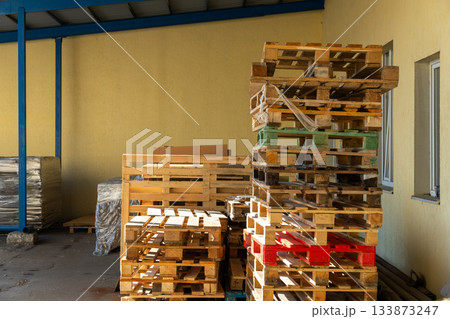 Stacks of wooden pallets are stored in an industrial warehouse yard Stacks of wooden pallets are stored in an industrial warehouse yard 133873247