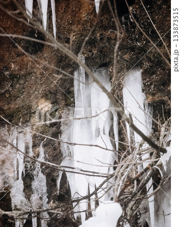Frozen Waterfall In Bad Urach, Baden Wuerttemberg: Dramatic Winter Ice Formations With Icicles And Snow Covering Rocks And Bare Trees 133873515