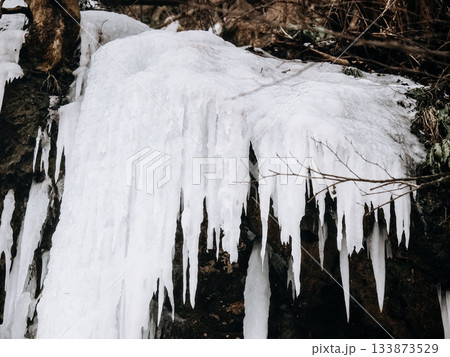 Frozen Waterfall In Bad Urach, Baden Wuerttemberg: Dramatic Winter Ice Formations With Icicles And Snow Covering Rocks And Bare Trees 133873529