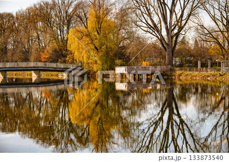 Autumn Lakeside Scenery Along The Amper River In Fuerstenfeldbruck: Calm Water Reflecting Bridge, Colorful Trees, And Lakeside Pavilion In Warm Evening Light Autumn Lakeside Scenery Along The Amper River In Fuerstenfeldbruck: Calm Water Reflecting Bridge, Colorful Trees, And Lakeside Pavilion In Warm Evening Light 133873540