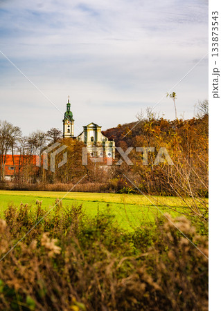 Historic Fuerstenfeldbruck Monastery In Bavaria: Baroque Church Tower Rising Above Autumn Trees And Open Green Fields Under Soft Daylight Historic Fuerstenfeldbruck Monastery In Bavaria: Baroque Church Tower Rising Above Autumn Trees And Open Green Fields Under Soft Daylight 133873543