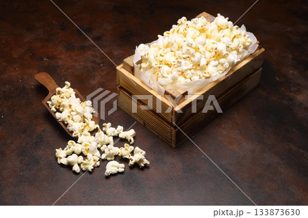 popcorn in a small wooden crate, isolated on dark background. popcorn in a small wooden crate, isolated on dark background. 133873630