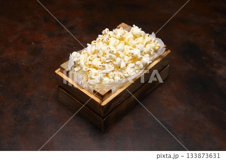 popcorn in a small wooden crate, isolated on dark background. 133873631