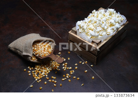 Corn with wooden scoop in burlap bag isolated on dark rustic background. Corn seeds in sack. Dry uncooked corn grains 133873634