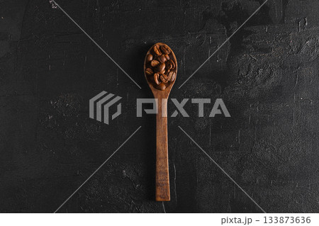 Coffee beans. On a spoon lie on a wooden background. 133873636