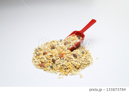 Oat flakes in Red spoon isolated on White background. Heap of oats for package of oatmeal or granola. Selective Focus. 133873784