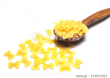 Raw pasta farfalle on wooden spoon on White background. Top view of Italian cuisine ingredient. 133873912