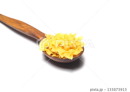 Raw pasta farfalle on wooden spoon on White background. Top view of Italian cuisine ingredient. Raw pasta farfalle on wooden spoon on White background. Top view of Italian cuisine ingredient. 133873913