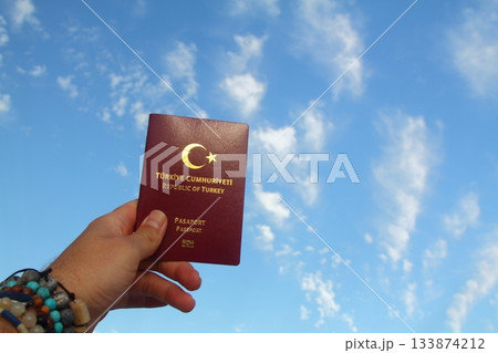 male hand with turkish passport blue sky and shining sun male hand with turkish passport blue sky and shining sun 133874212
