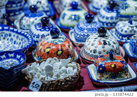 Bunzlaue ceramics and polish pottery with colorful traditional patterns displayed on a market stall table, showcasing handcrafted artisan tableware. Bunzlaue ceramics and polish pottery with colorful traditional patterns displayed on a market stall table, showcasing handcrafted artisan tableware. 133874422