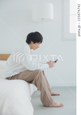 寝室でスマホを見る若い男性 寝室でスマホを見る若い男性 133874742