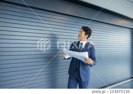 店舗物件の前で考えるビジネスマン 133875130