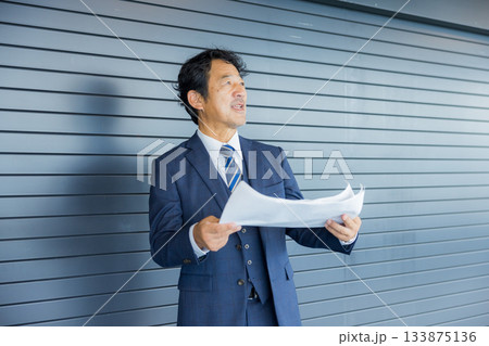 店舗物件の前で考えるビジネスマン 133875136