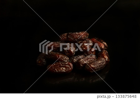 Dates on a black background. Dried fruits. Dried dates lie next to each other Dates on a black background. Dried fruits. Dried dates lie next to each other 133875648